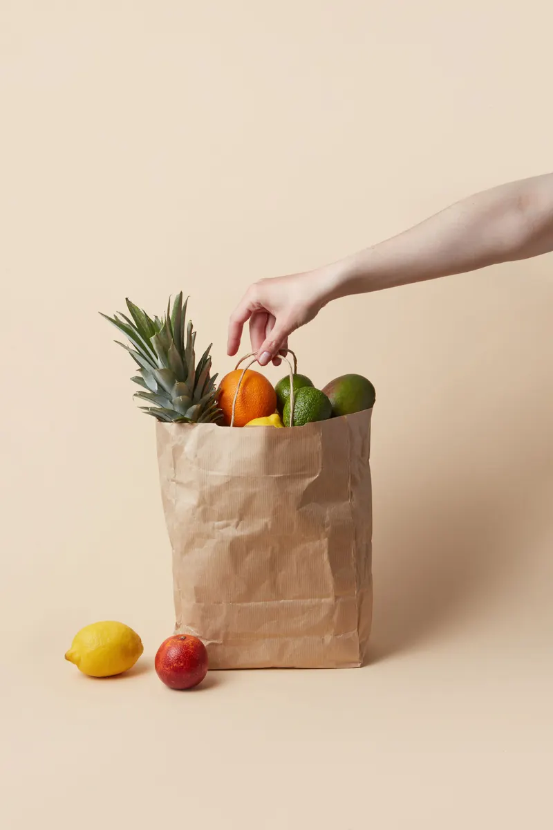 A paper grocery bag full of fresh fruit on a kitchen counter